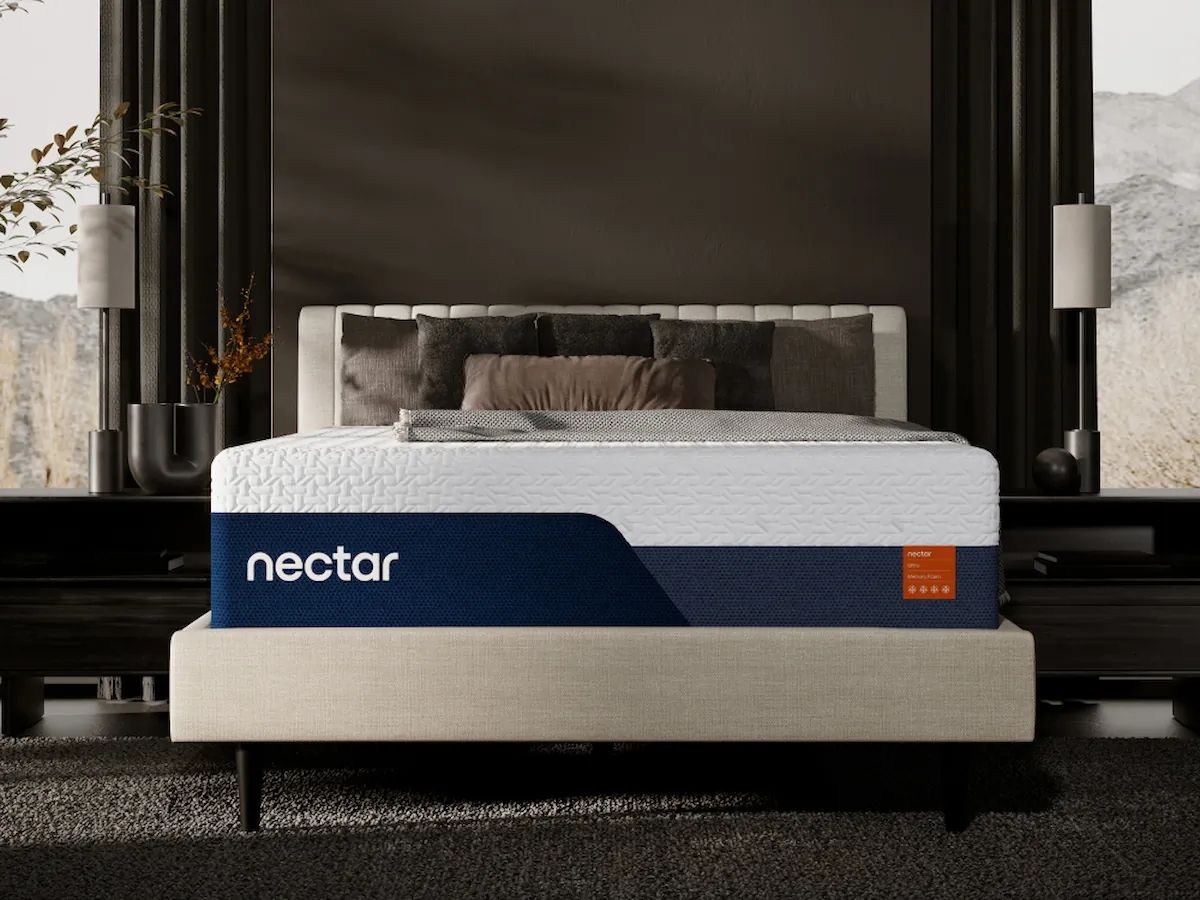 Nectar Ultra Memory Foam mattress on beige frame with white quilted top, navy blue side panel logo, and grey pillows in