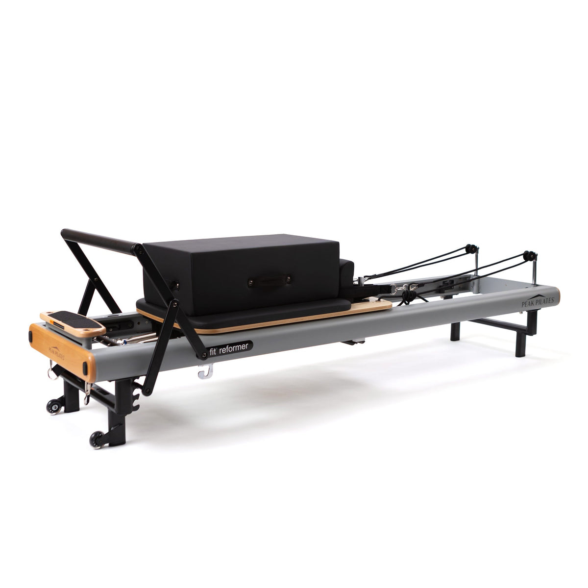 Studio shot of grey Peak Pilates fit Reformer with light wood footbar, black padded long box on carriage, and visible
