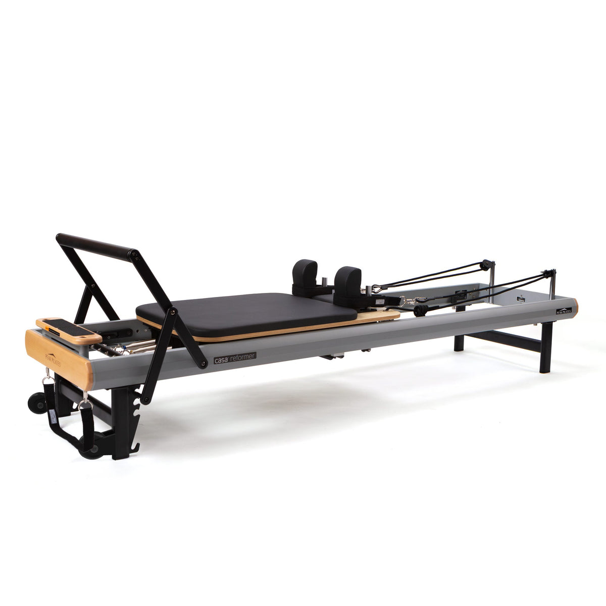 Grey and wood home Pilates reformer with black upholstery, padded headrest, and foldable foot bar on white background