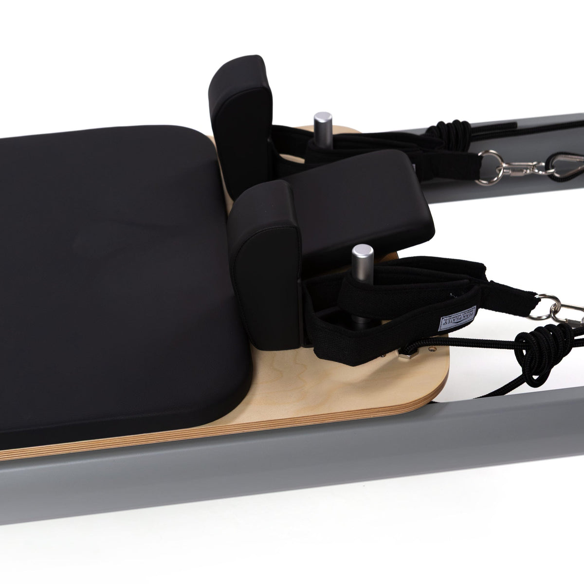 Macro shot of black padded shoulder rests, adjustable foot bar, layered plywood, and webbing straps on carriage