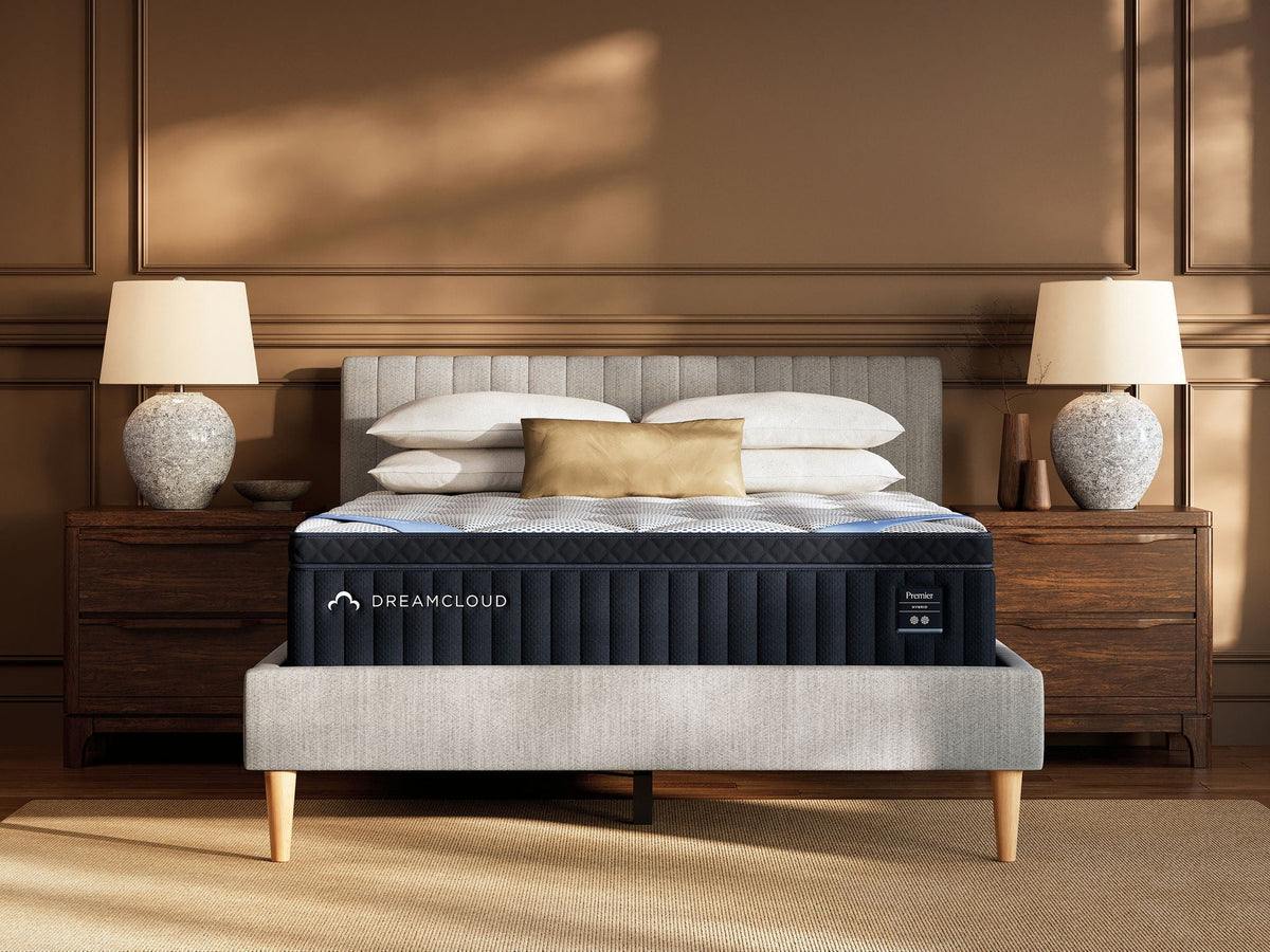 DreamCloud hybrid mattress on grey upholstered frame in bedroom with wooden nightstands
