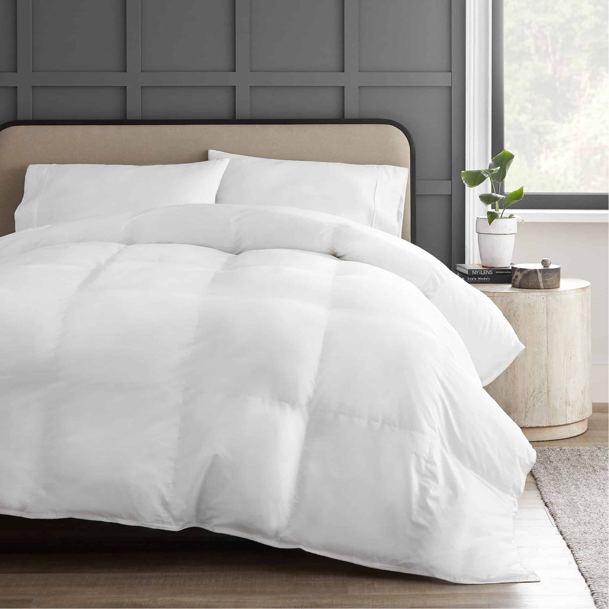 Fluffy white microfiber fill comforter with square quilted pattern draped over bed in serene room