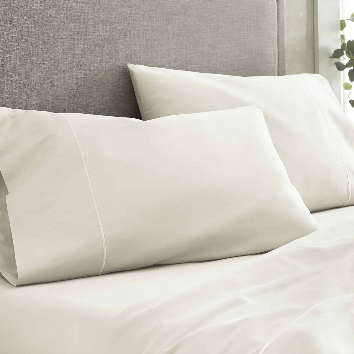 Close-up of off-white pillowcases showing elegant sheen and precise edge stitching
