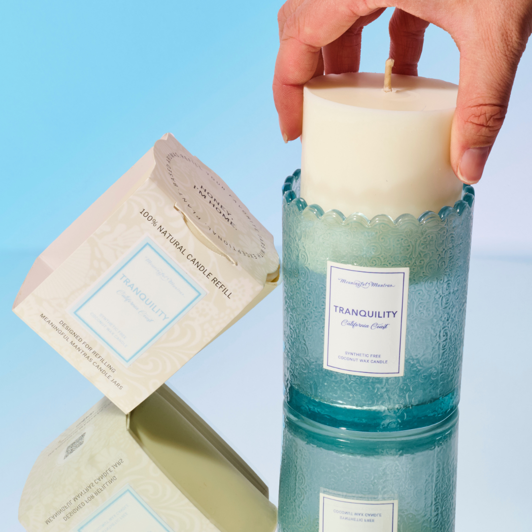 Hand inserting white solid wax refill cylinder into empty blue embossed glass jar for reuse