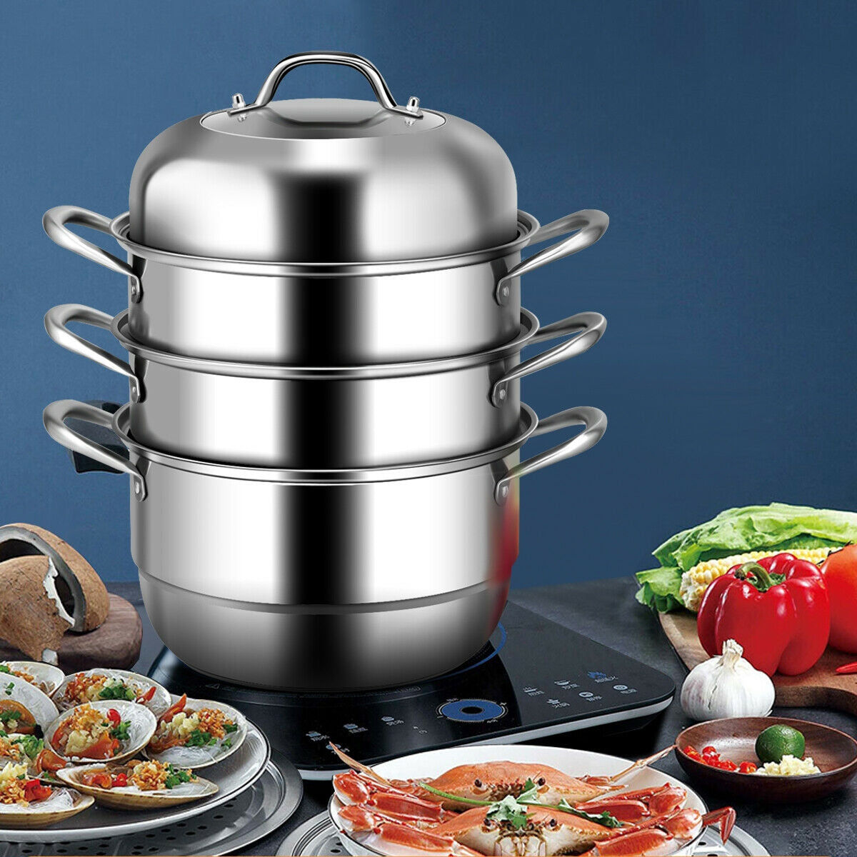 Assembled 3 tier stainless steel steamer set on black induction cooktop beside plates of cooked seafood and vegetables