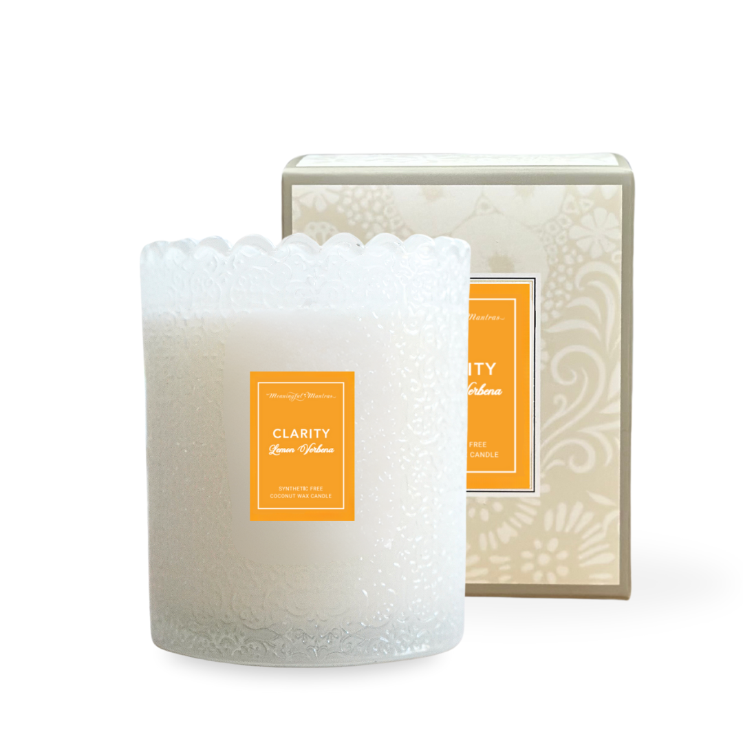 Frosted glass candle with embossed floral pattern and scalloped rim beside orange-labeled box