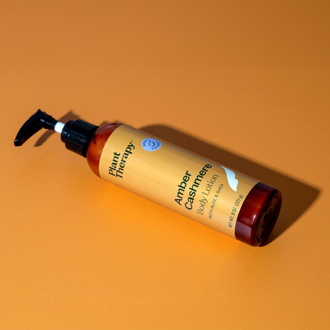 Amber lotion bottle lying diagonally on orange surface casting sharp shadow