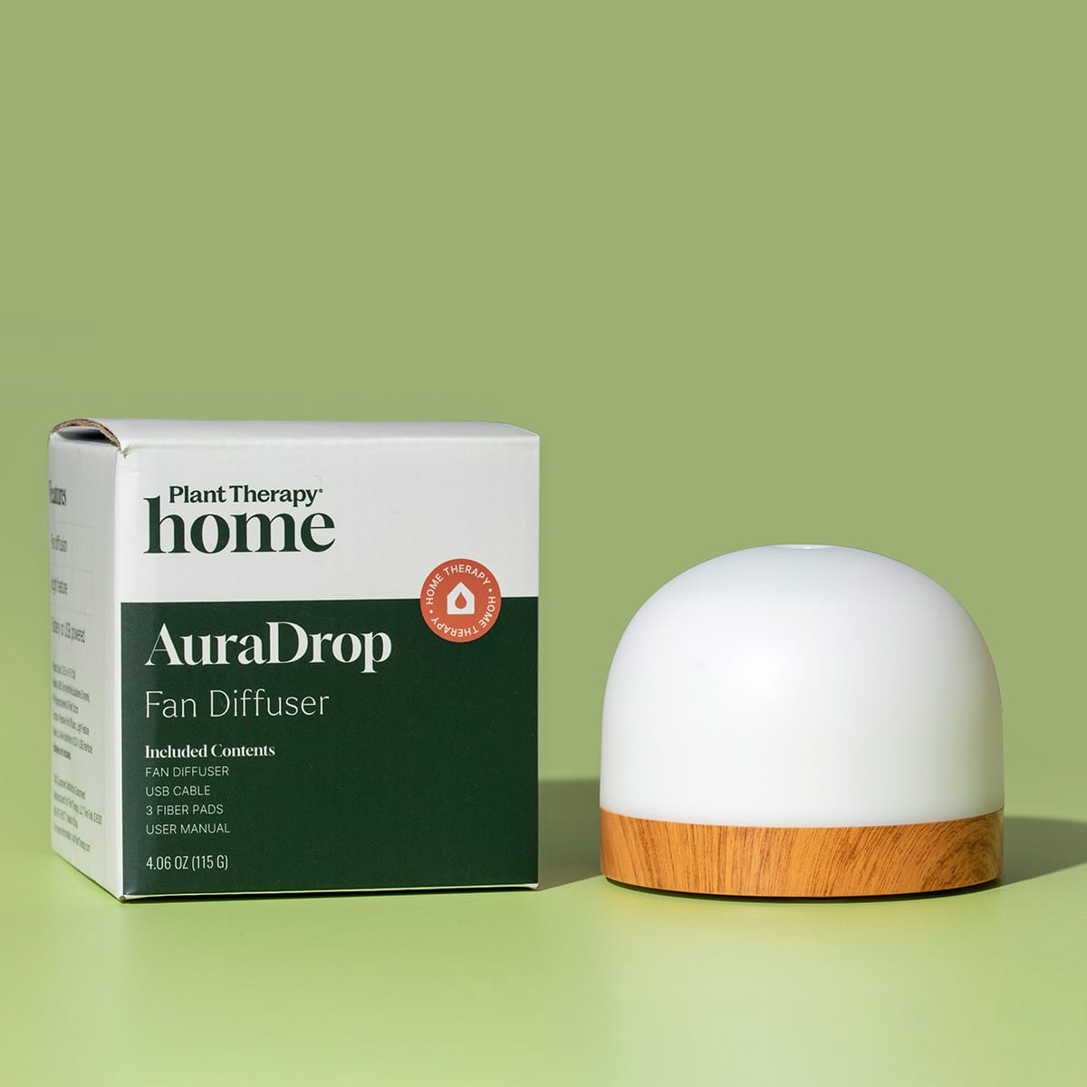 Studio shot of white and wood-accented AuraDrop Fan Diffuser next to packaging box on sage green backdrop