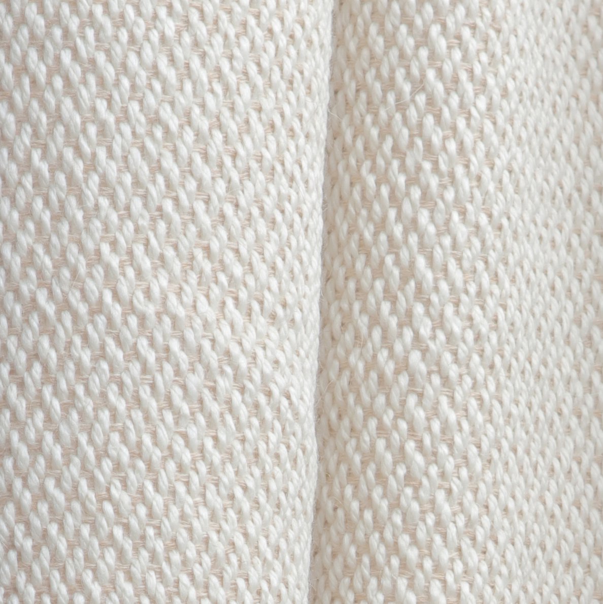 Macro shot of luxury wool throw blanket fabric revealing tight diagonal twill weave pattern and natural tweed effect texture