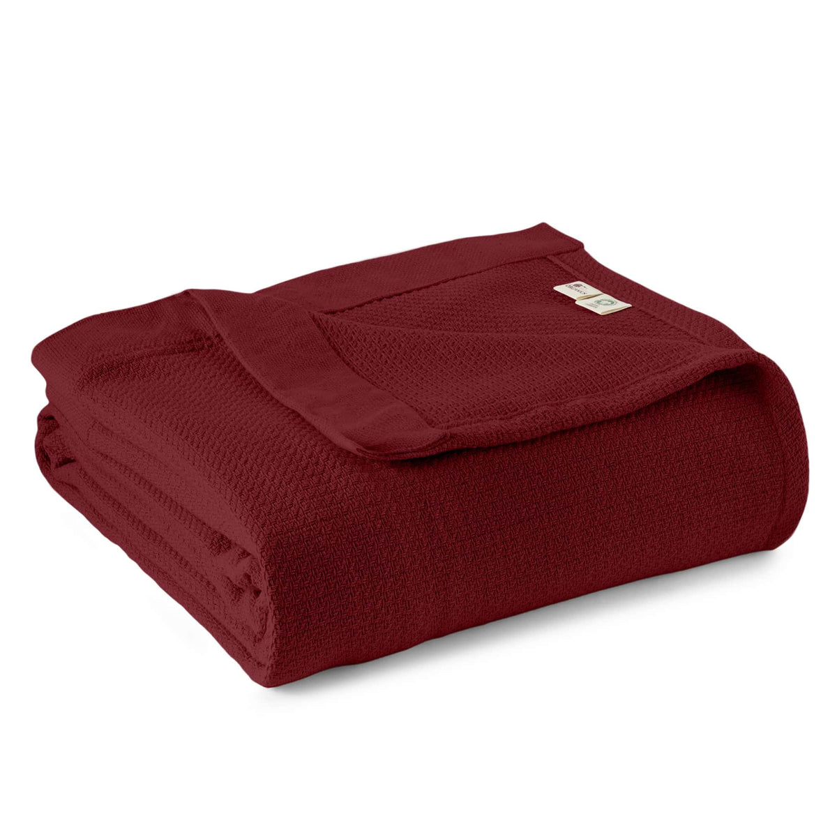 Neatly folded deep burgundy red organic woven blanket displaying waffle weave and brand tag