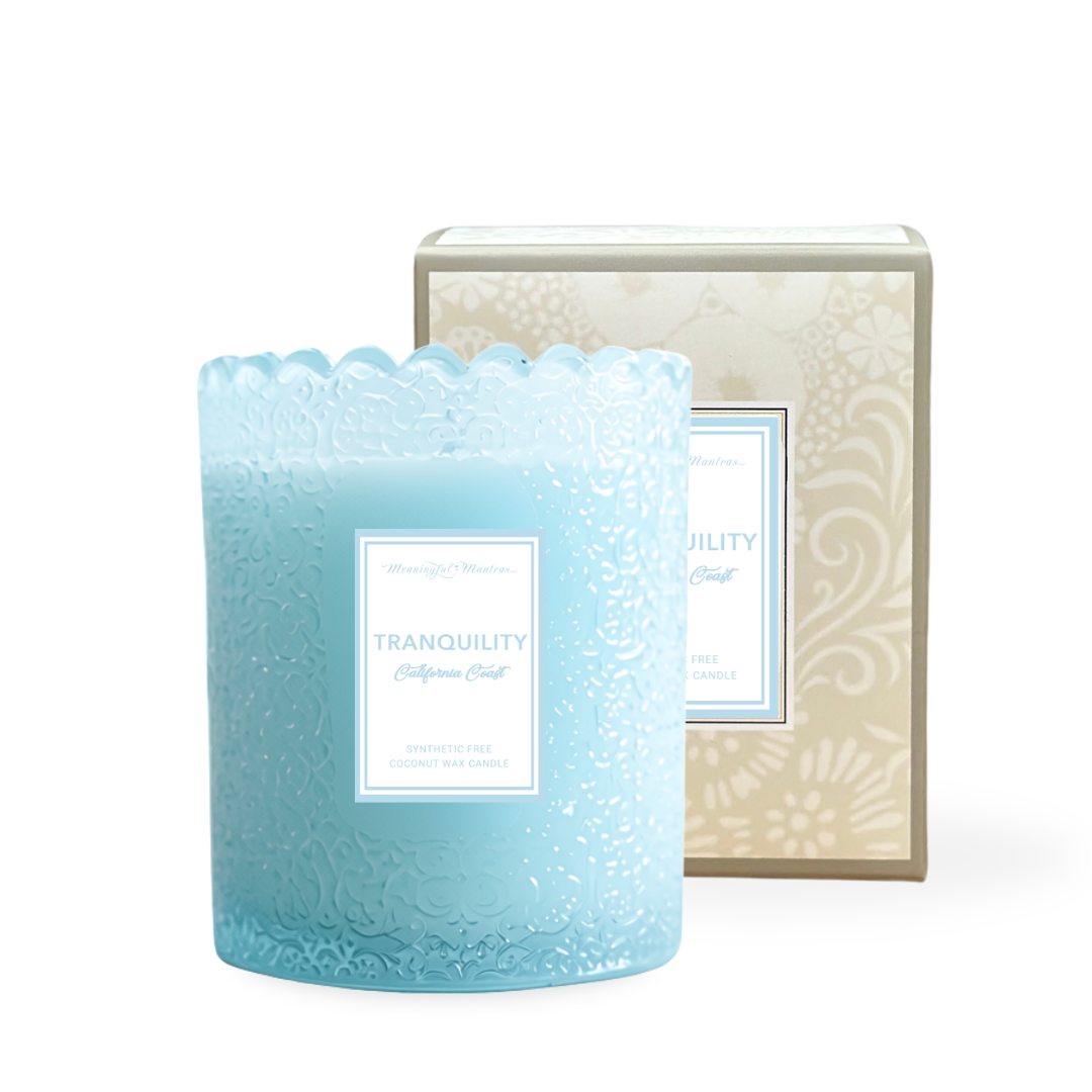 Light blue embossed glass jar candle with scalloped rim and white label reading Tranquility California Coast