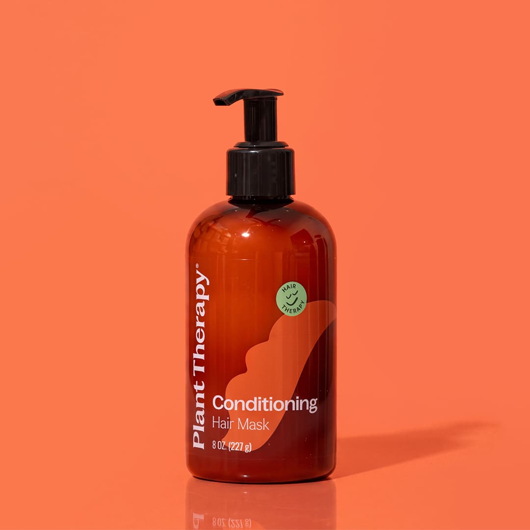 Amber hair mask bottle against vibrant orange background with reflective surface