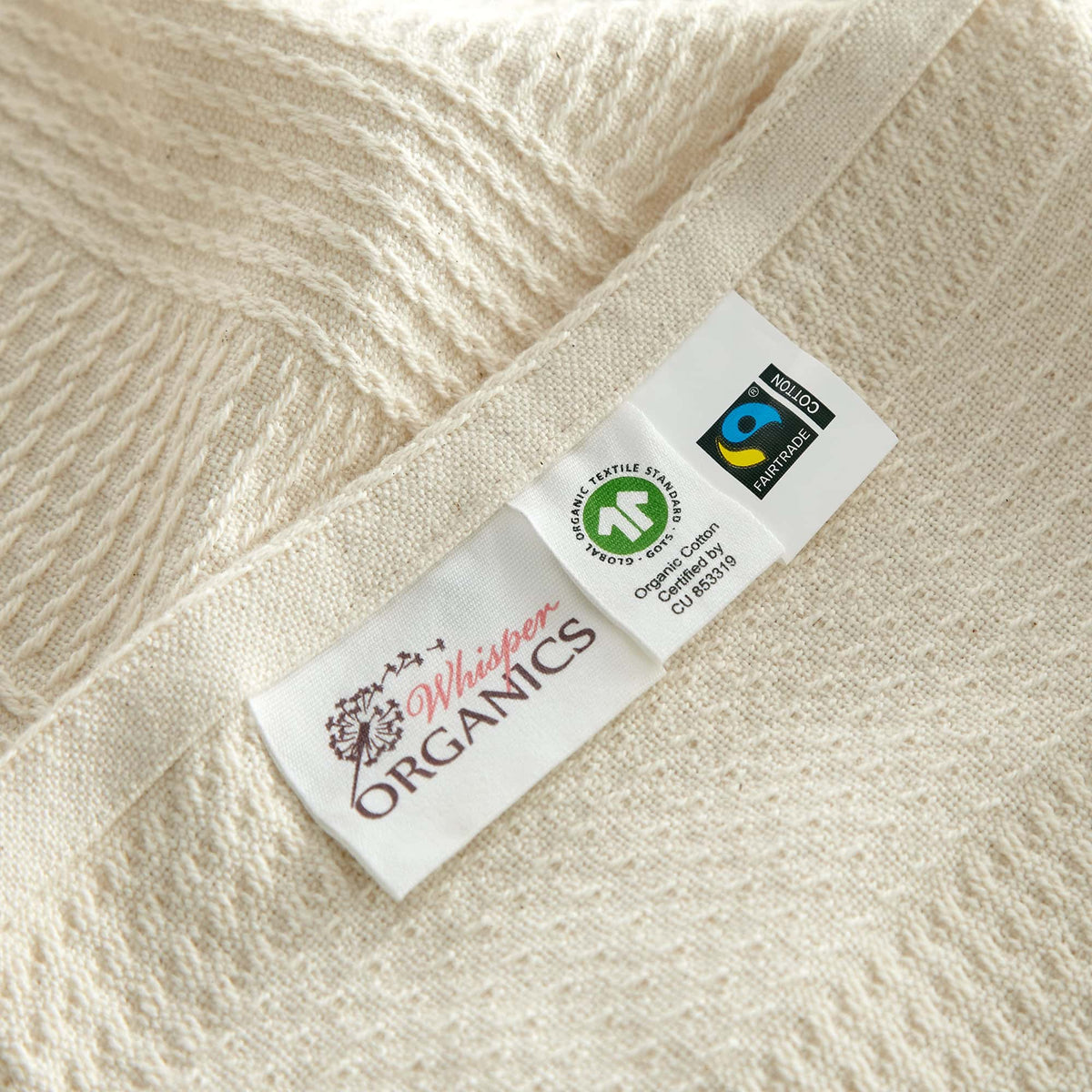 Product label showing Whisper Organics logo alongside GOTS and Fairtrade certification marks