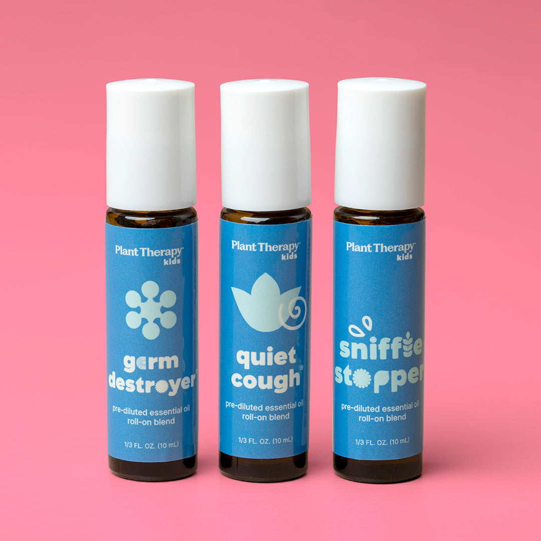 Three amber roll-on bottles with white caps against a pink background showing volume markings of 10 mL.
