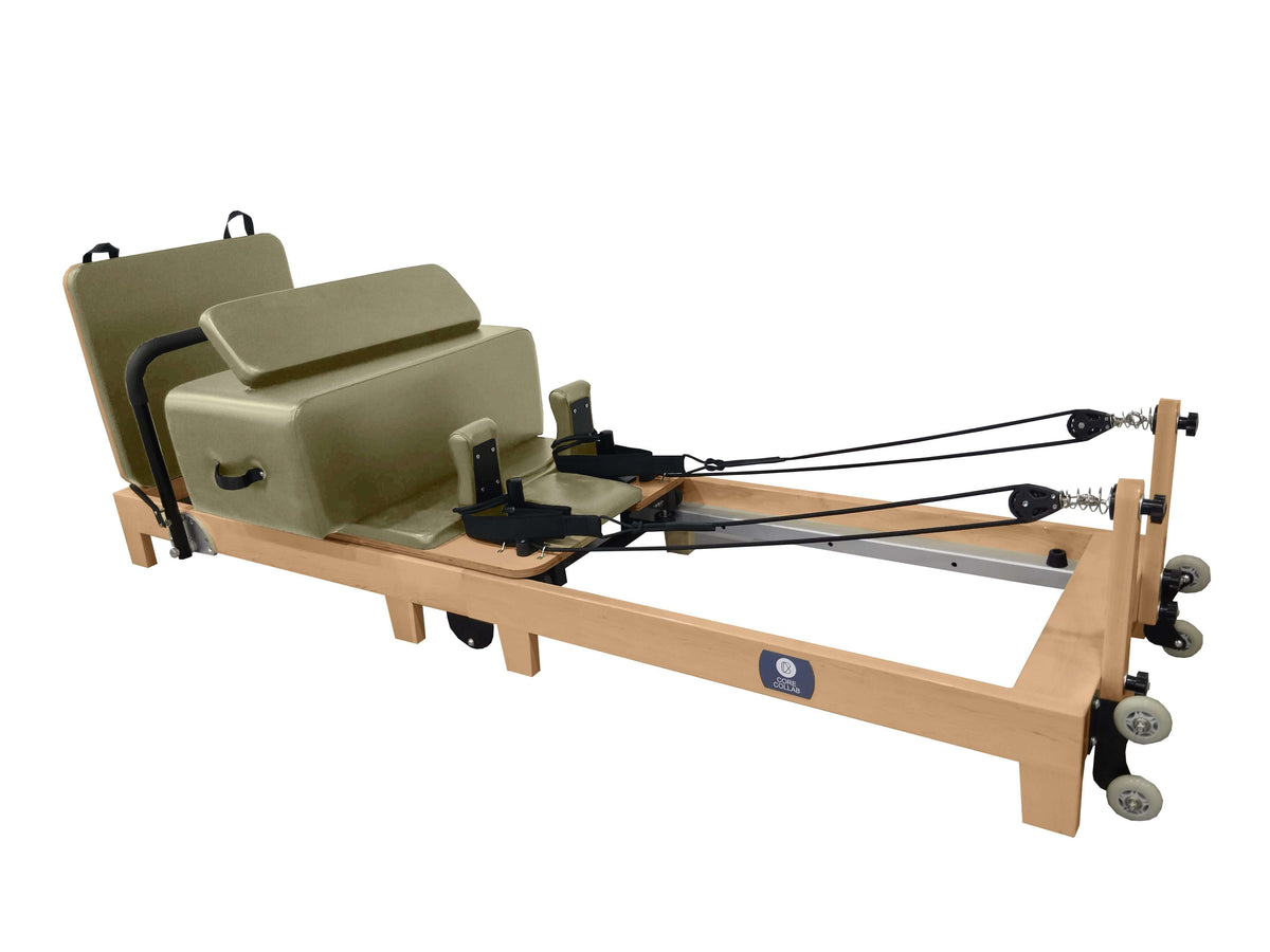 Olive green upholstery reformer with wooden construction, black hardware, pulley system, and transport wheels