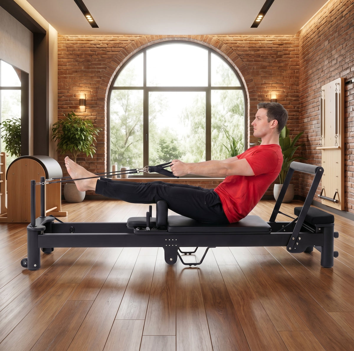 Man in red shirt exercising on a black reformer machine against exposed brick walls demonstrating smooth carriage glide