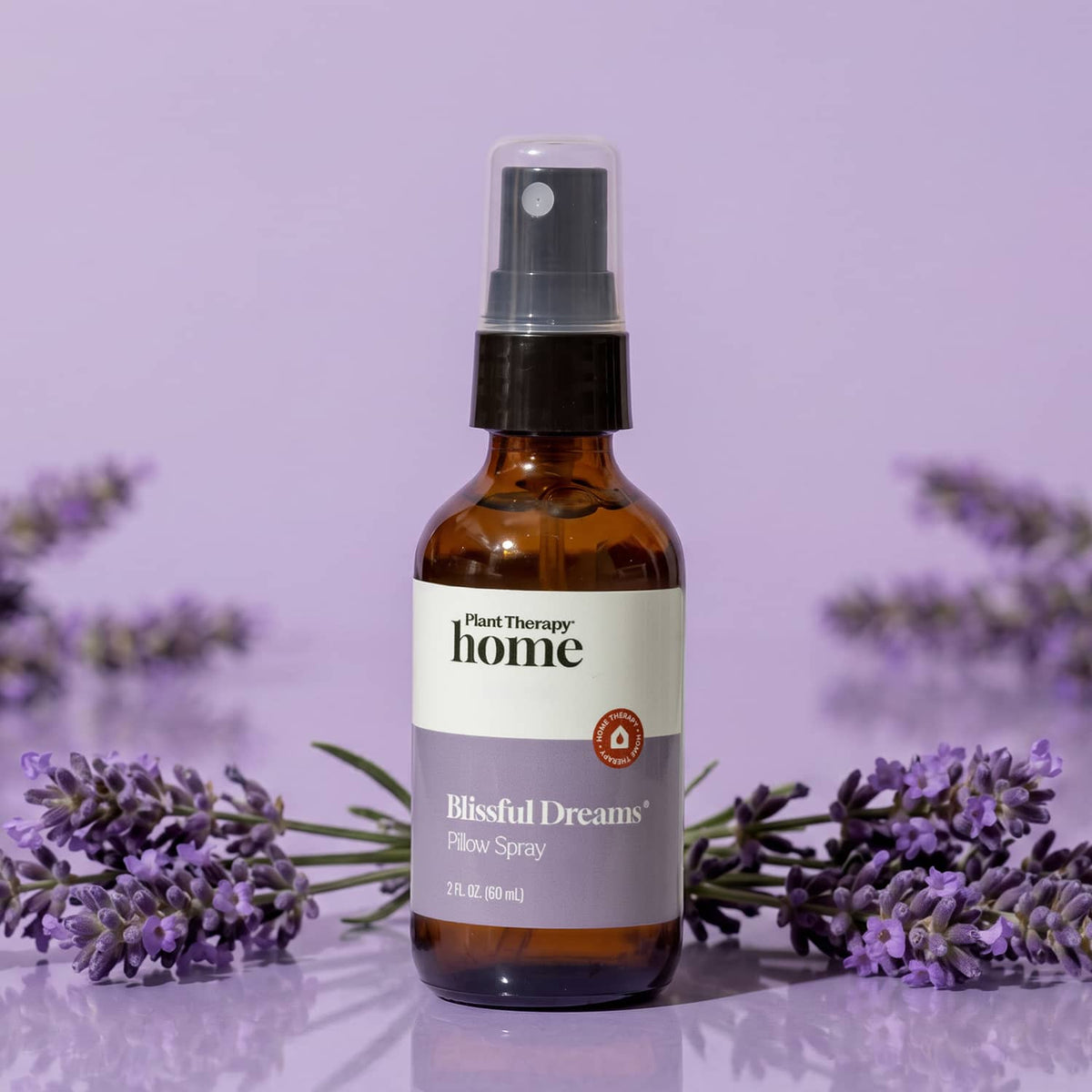 Amber spray bottle surrounded by fresh lavender sprigs against purple backdrop