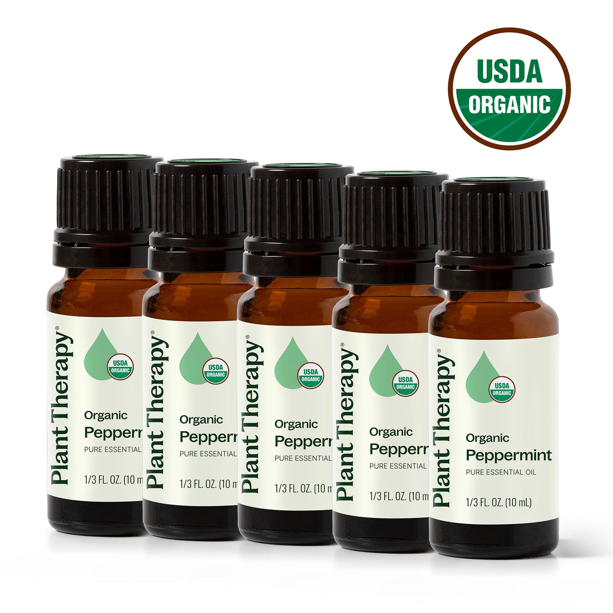 Five amber glass bottles of organic peppermint essential oil in a row with USDA Organic seal