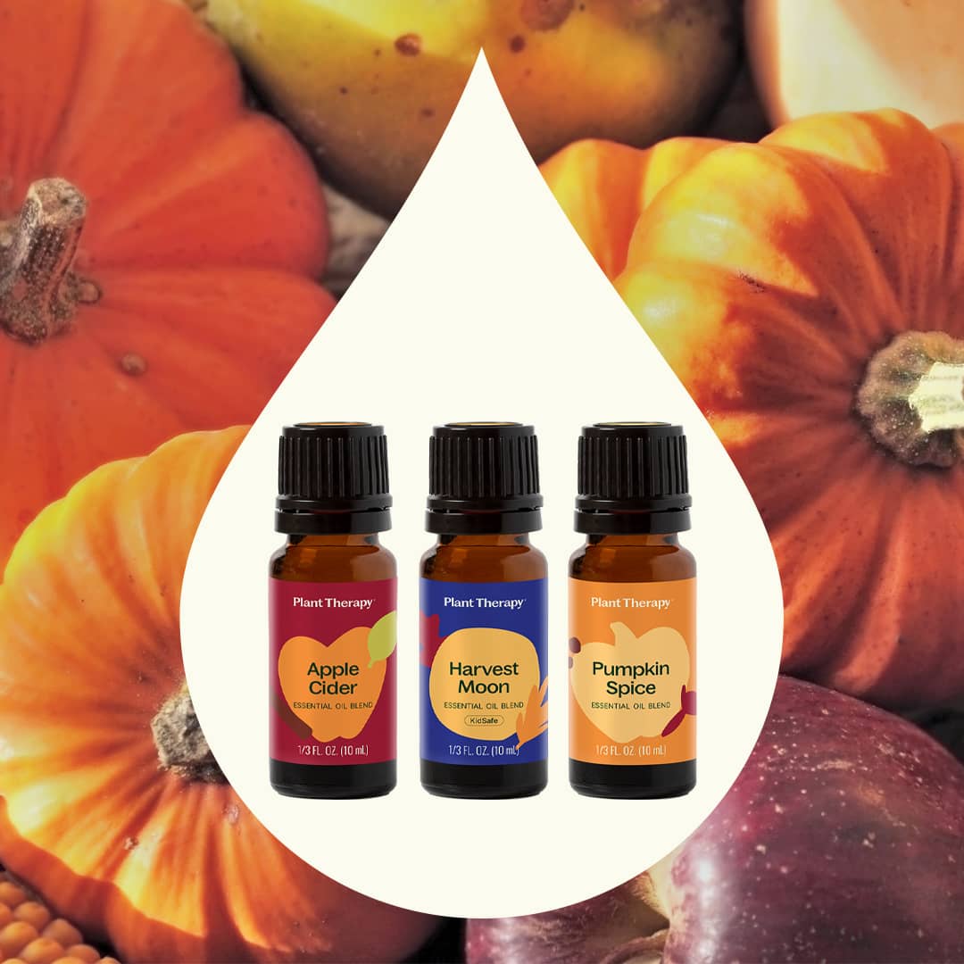 Three essential oil bottles framed inside a large white teardrop shape against a blurred background of orange pumpkins and