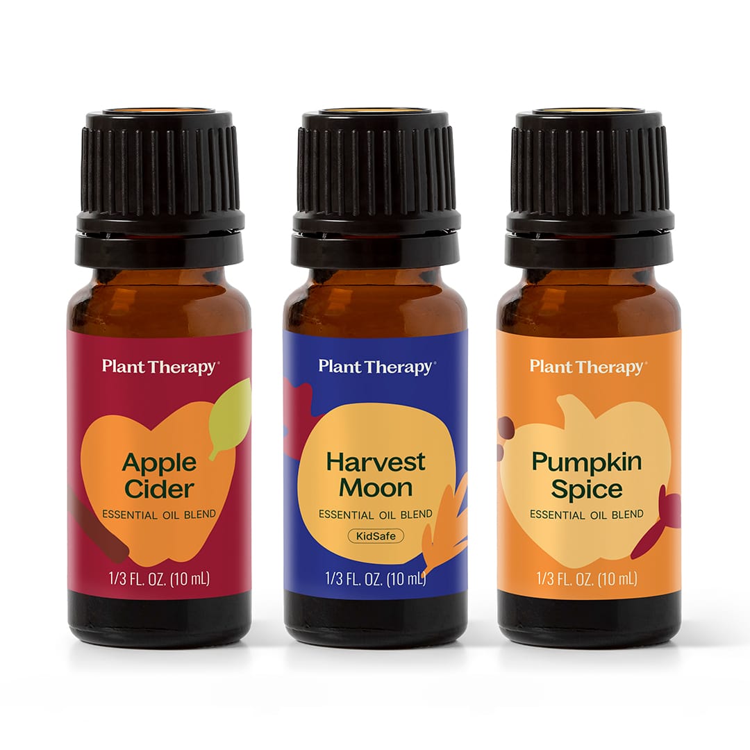 Three amber Plant Therapy essential oil bottles with black caps on white background, labeled Apple Cider, Harvest Moon, and