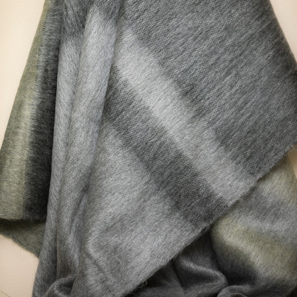 Close-up of brushed alpaca fiber texture with soft sheen and gradient between dark gray and olive stripes