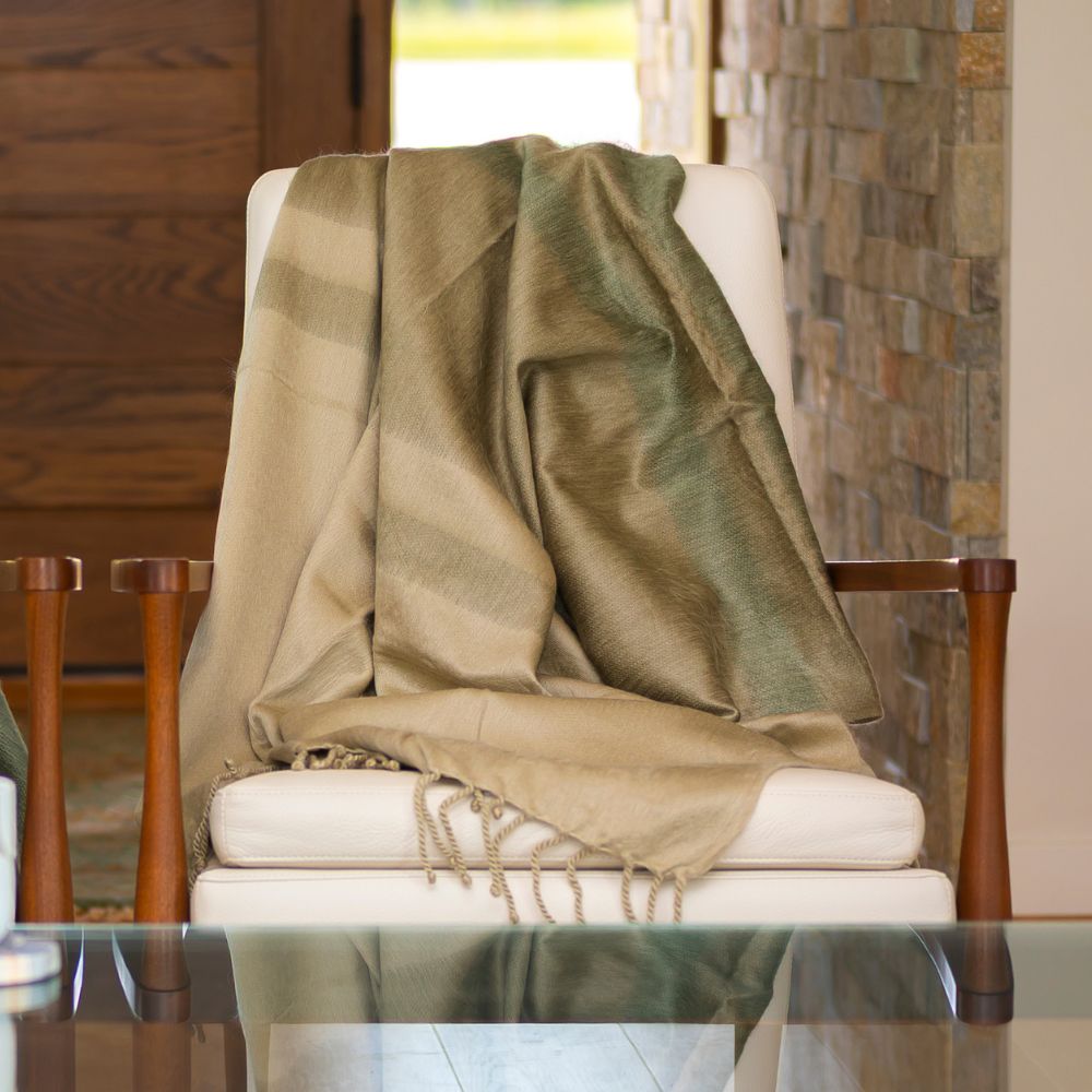 Tobacco olive and khaki handwoven alpaca throw blanket draped over a white armchair in natural light