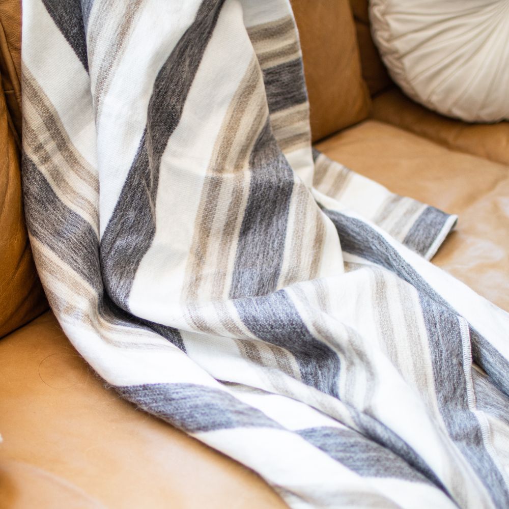 Cream and camel striped alpaca throw draped on tan leather sofa