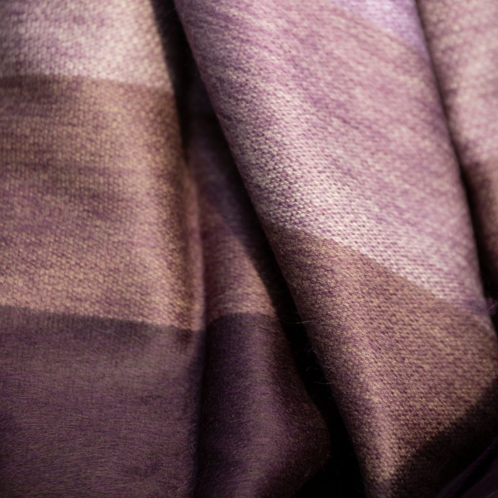 Macro view of brushed alpaca fabric showing dusty lavender to plum woven texture