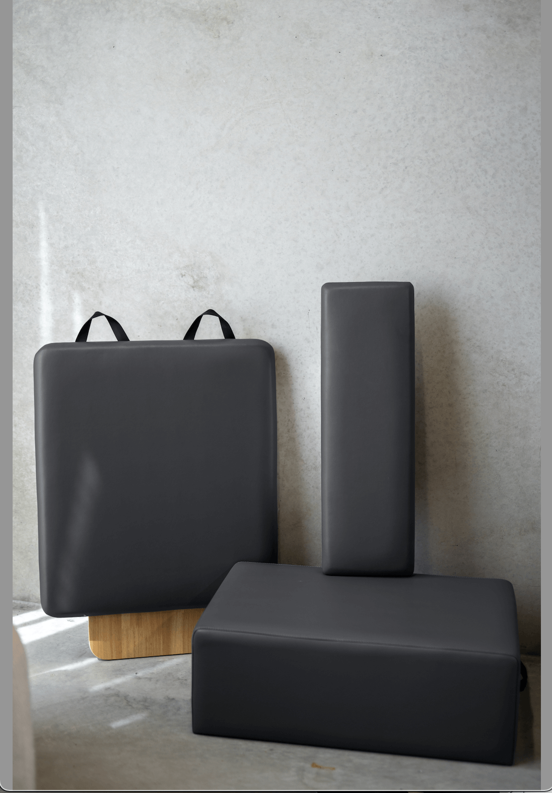 Dark charcoal grey Pilates accessories set with box, platform, and jump board on concrete