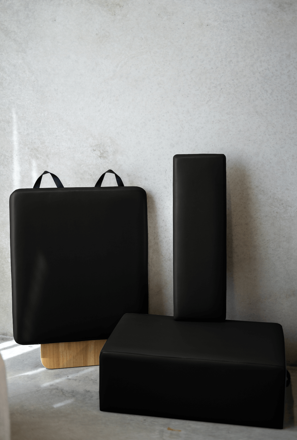 Deep black Pilates props set including box, vertical platform, and jump board on grey surface