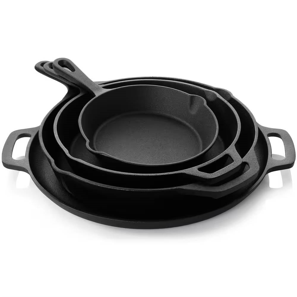 Three nested black cast iron skillets with matte finish and loop handles on white background