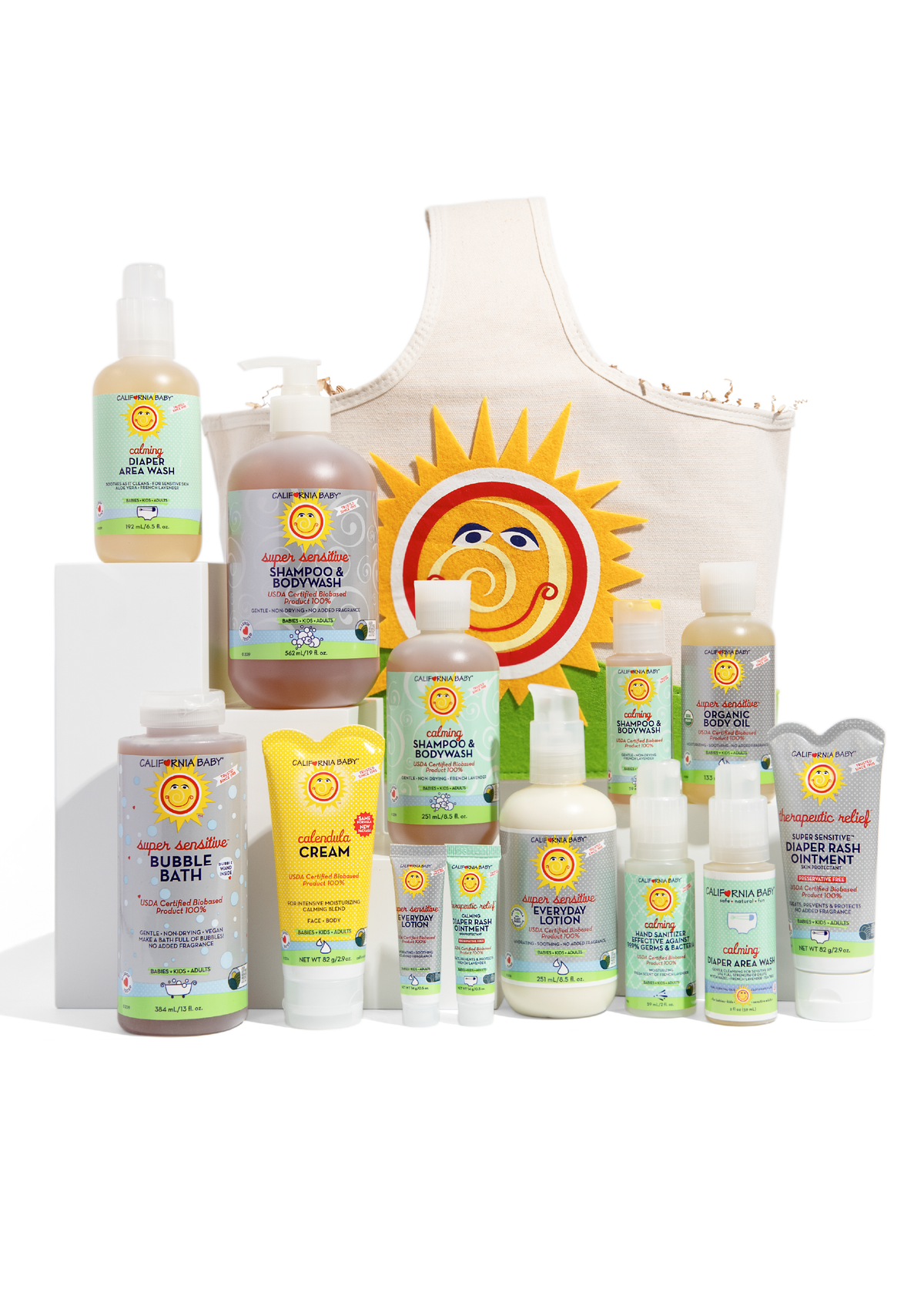 California Baby newborn gift set products on white blocks beside cream tote with sun logo