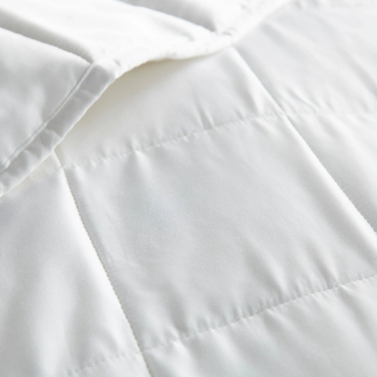 Macro shot of white duvet comforter showing the smooth cloud-soft texture of the viscose shell and precise square quilted