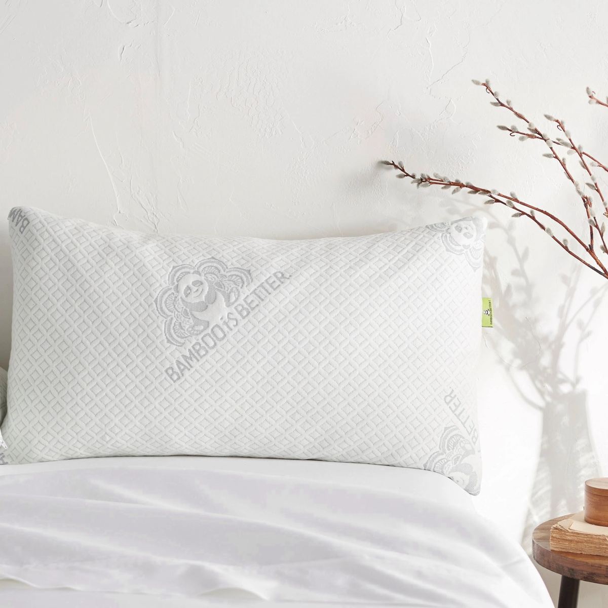 Single upright white pillow showing quilted cover, central logo, and green side tag