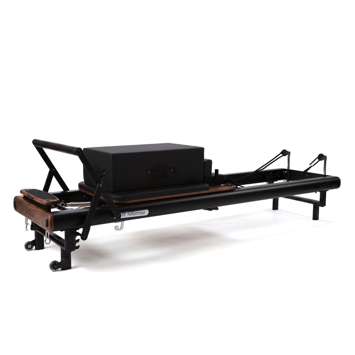 Side profile of black Peak Pilates fit Reformer with dark walnut wood accents, black long box, and black straps against white