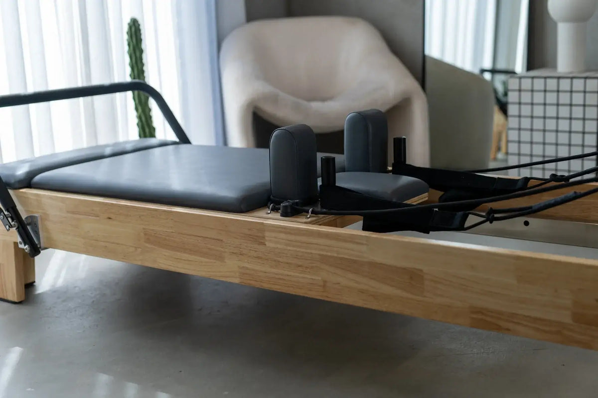 Low angle close-up of light wood frame, grey sliding carriage, and black shoulder rests with cable system