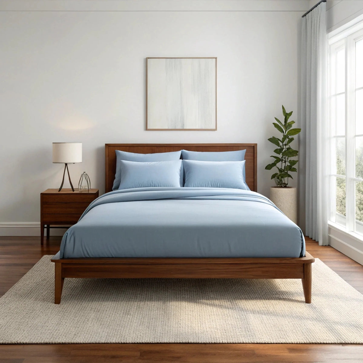 Light blue bamboo sheet set on wooden platform bed in bright minimalist bedroom with neutral rug and potted plant