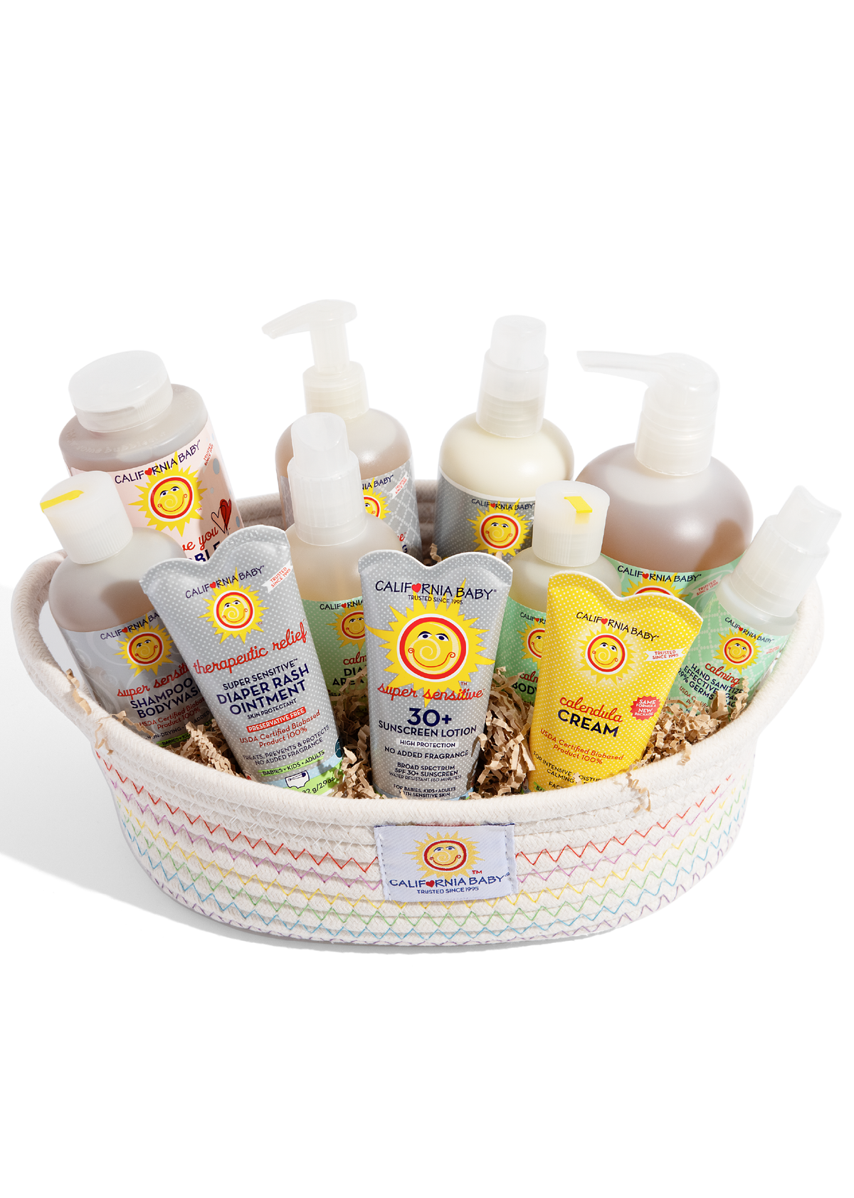 High-angle view of baby care items nestled in shredded paper inside a woven basket