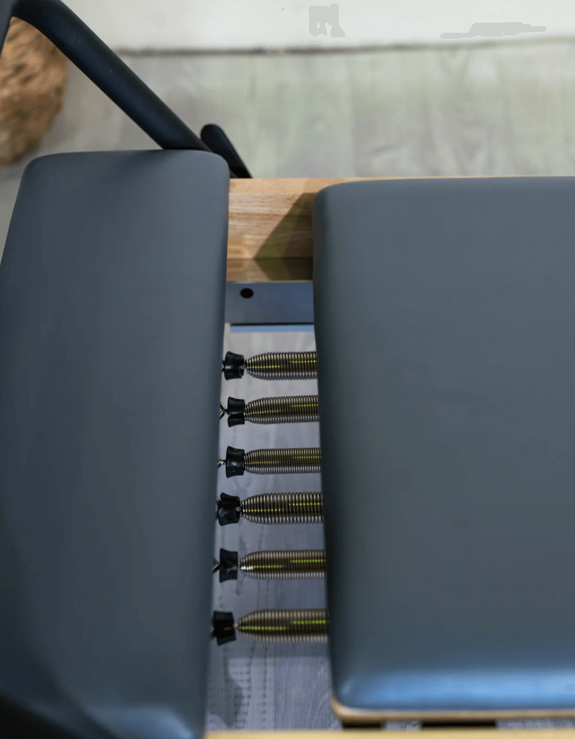 High-angle close-up of internal mechanics showing six metallic coil springs between gray upholstery sections and light wood