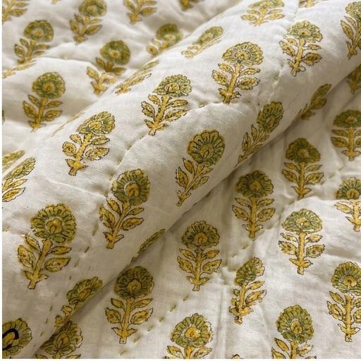 Macro shot of soft muslin cotton texture, visible quilting stitches, and detailed mustard yellow floral stems