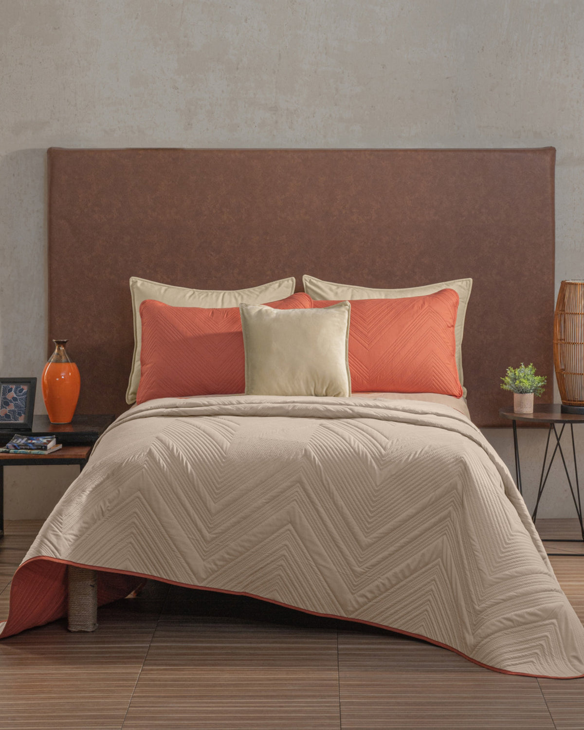 Beige raised chevron comforter with visible terracotta reverse hem styled with solid pillows against a brown upholstered