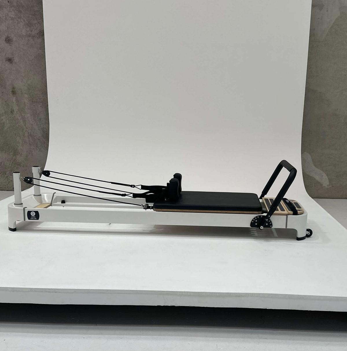 Black reformer side view displaying adjustment dial, wooden accents, and straps