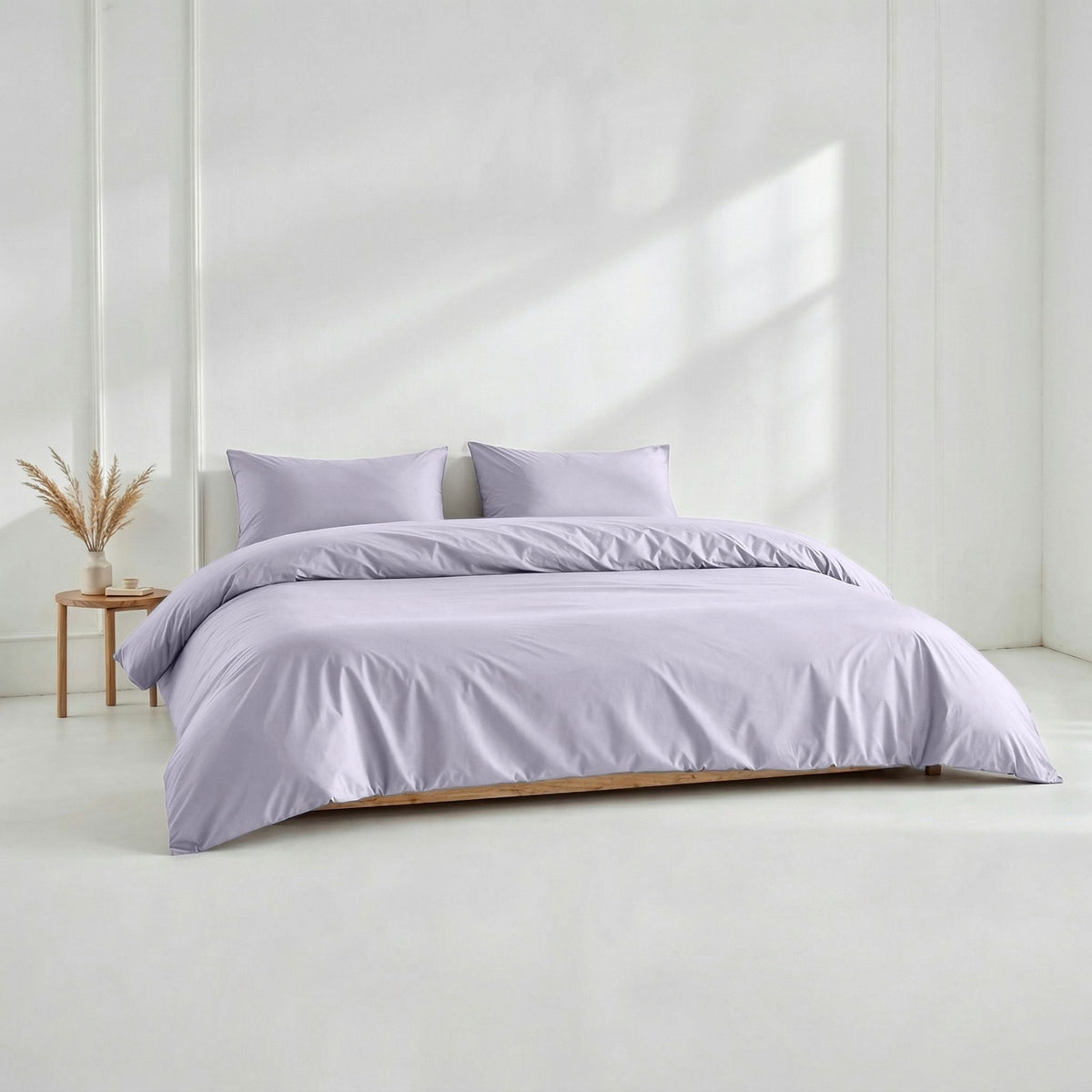Solid lavender sateen duvet cover set shown on a wooden platform bed against a white wall