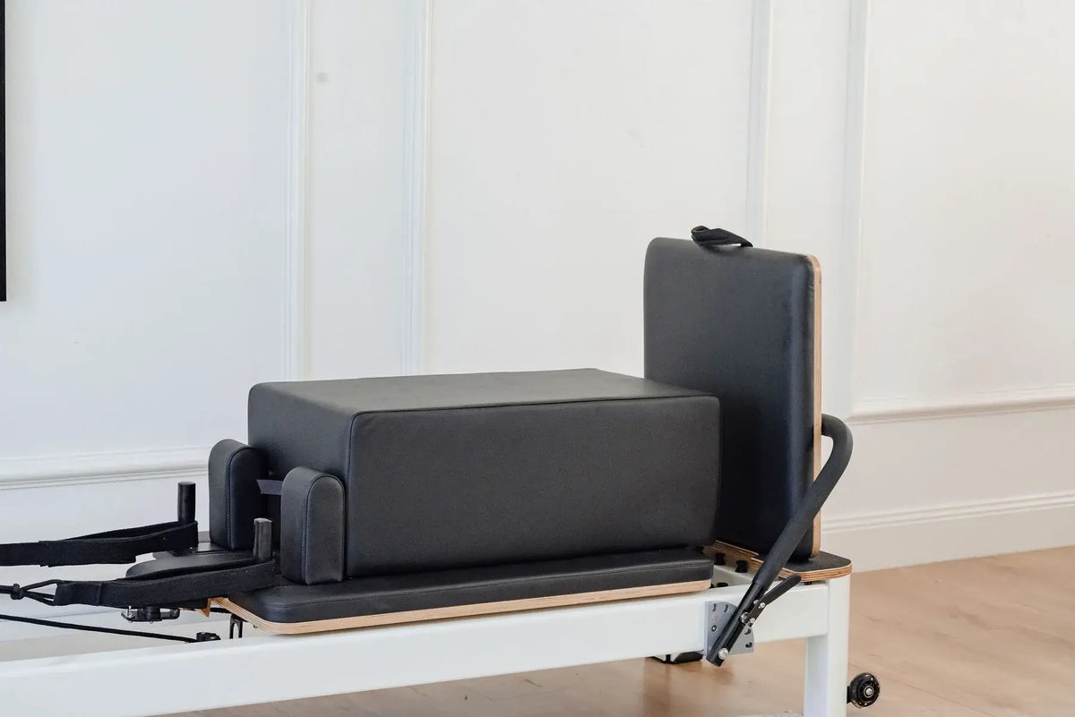 Black leather Reformer Box and Jumpboard attachment standing at head end