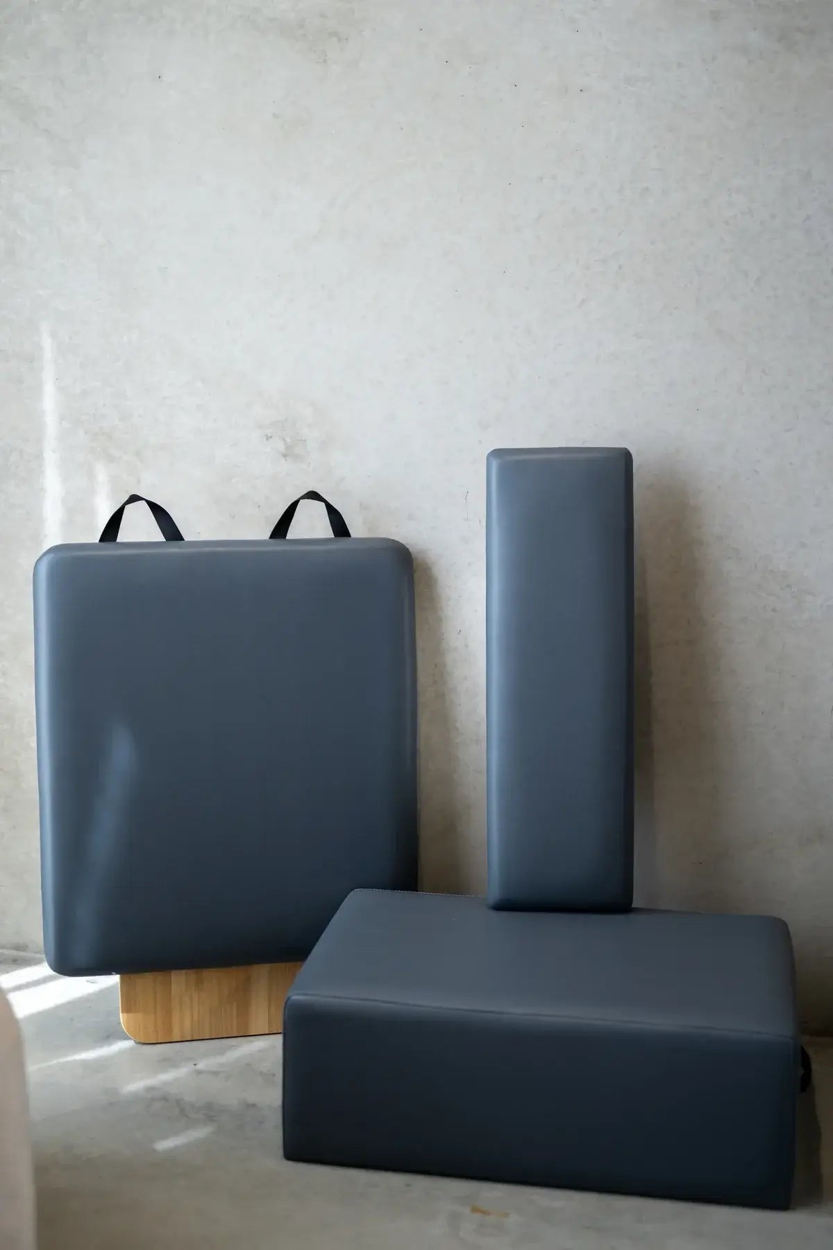 Detached black padded accessories including box and jumpboard against concrete wall