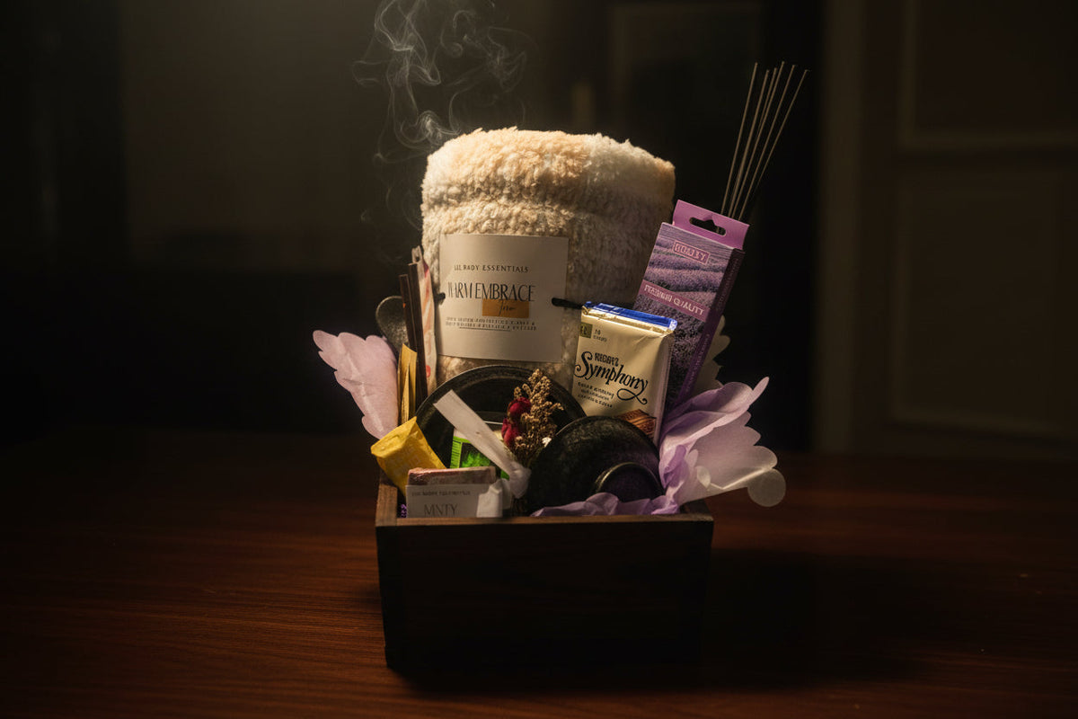 Wooden wellness crate with cream blanket and tea styled with light purple foliage accents on a wooden table under soft