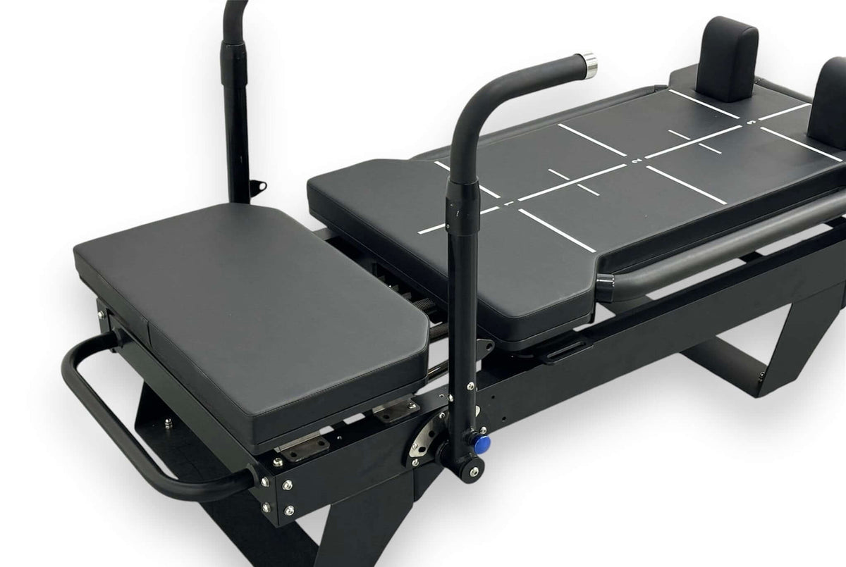 Close-up of adjustable padded seat, sliding carriage with white grid lines, and mechanical adjustment knobs on rail