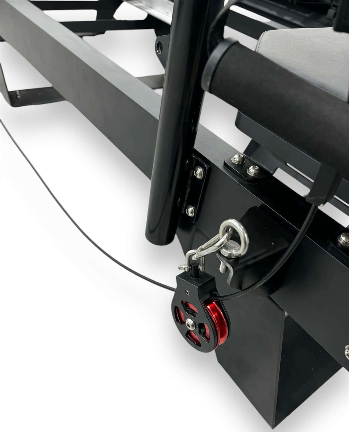Macro shot of red and black pulley wheel, silver hardware, bolts, and tension cable system on lower machine frame