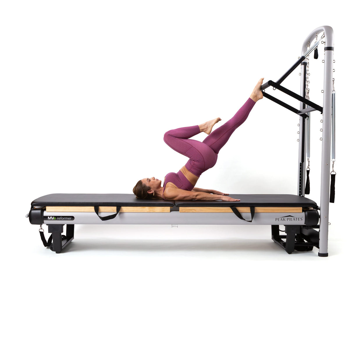 Female practitioner in purple activewear performing inverted exercise using tower footbar and black straps