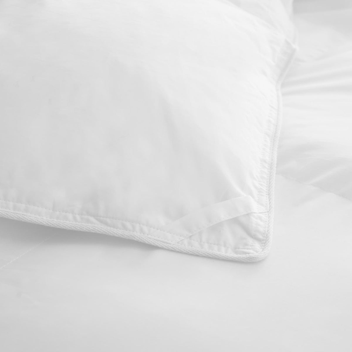 Close-up of reinforced hem stitching and soft percale weave texture on white comforter corner